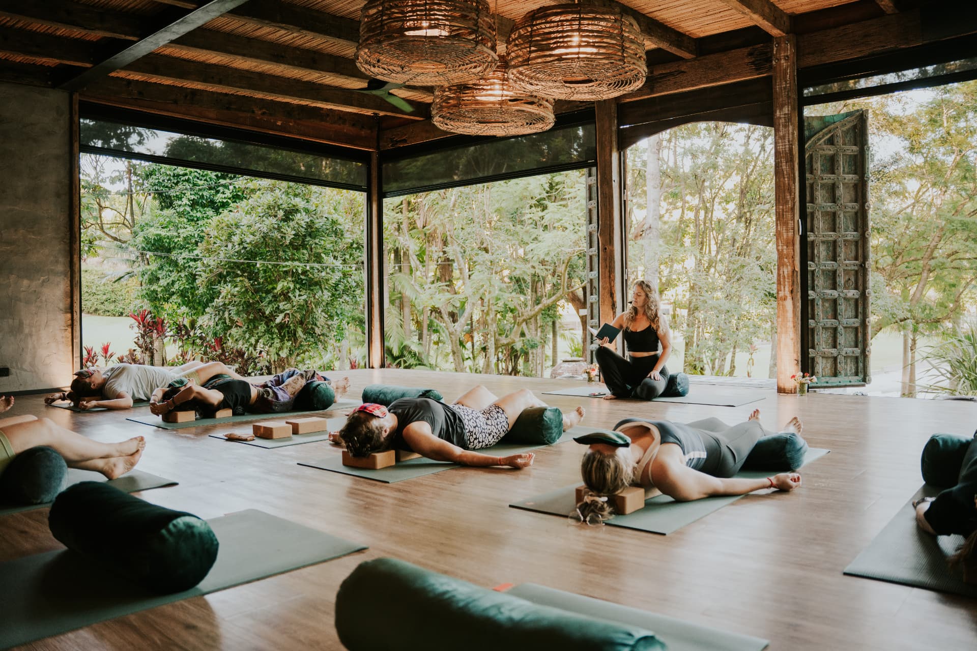 Women resting on mats in the open shala while Anastasia guides the practice at an Elementa Byron Bay day retreat