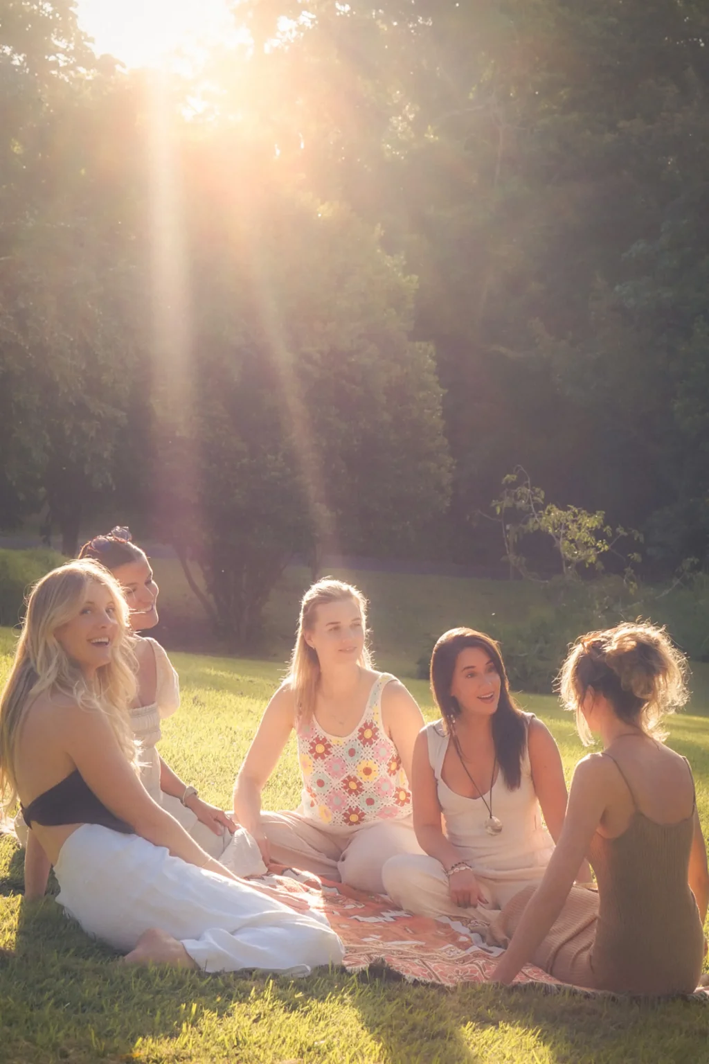 Women gathered in circle on the grass at golden hour during The Slow Life Retreat