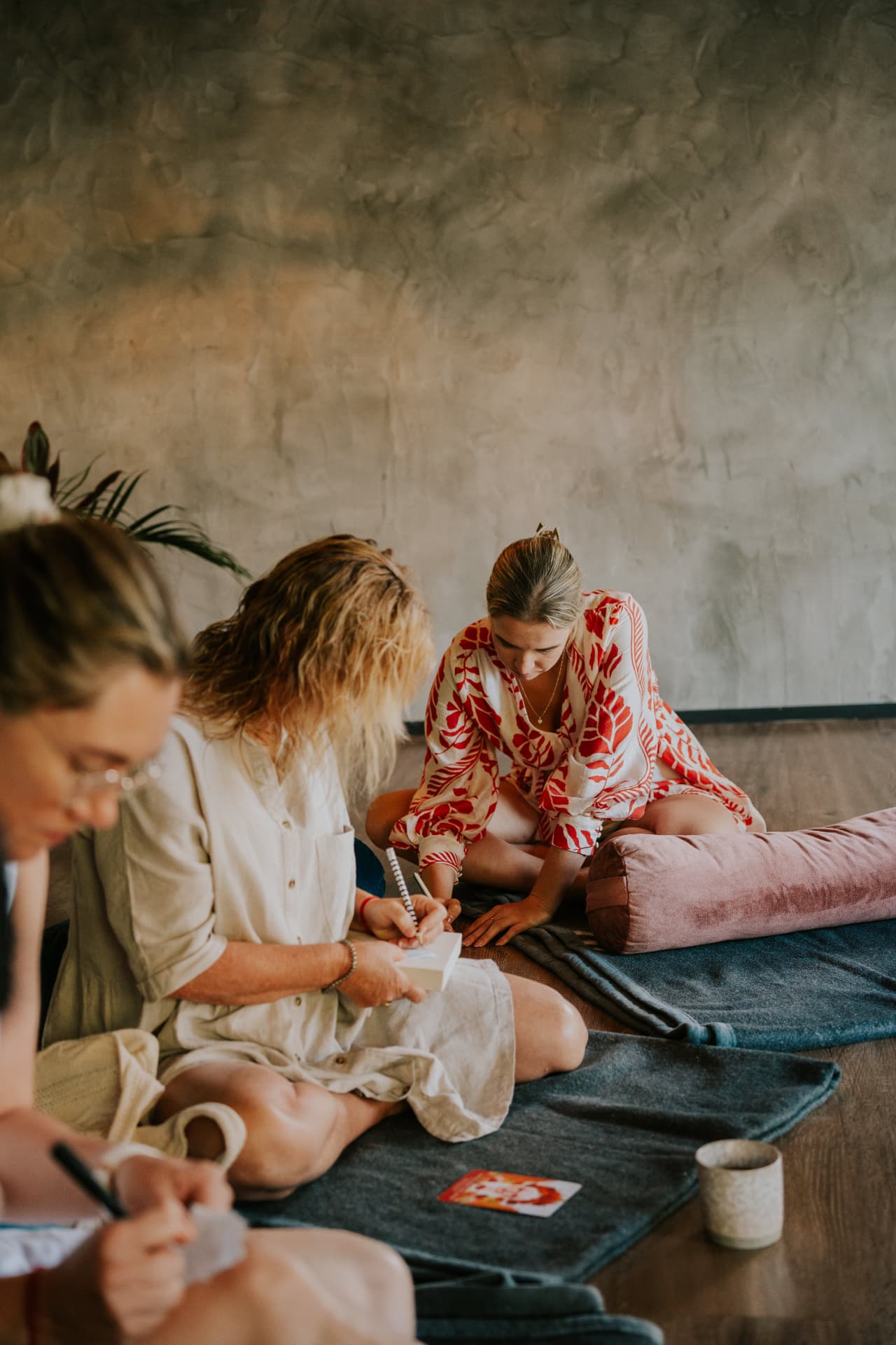 Women journaling together on floor cushions