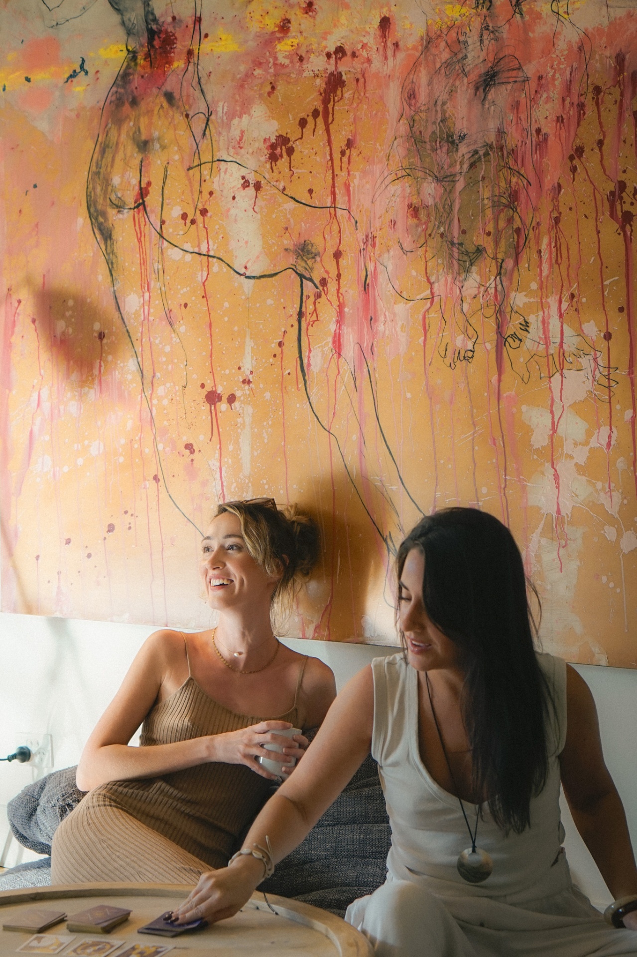 Women sharing tea beneath an artwork during an Elementa event