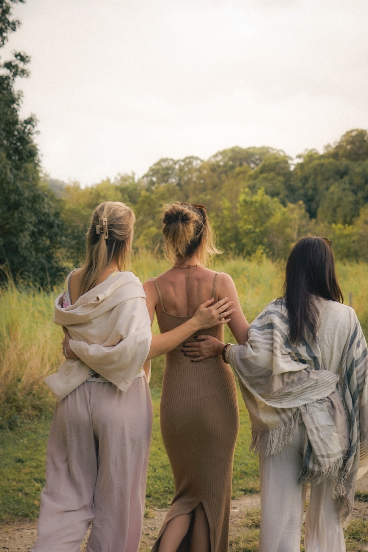 Three women walking arm in arm through retreat grounds